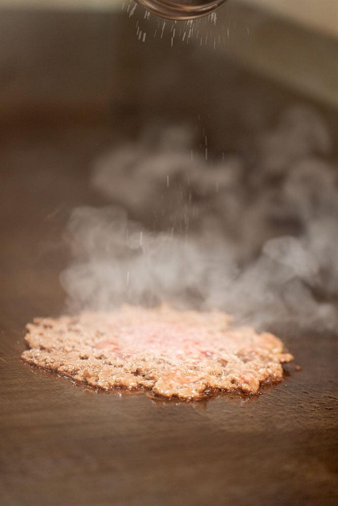 La carne aplastada y salada sobre la plancha