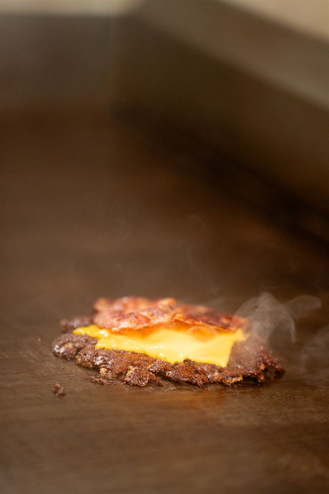 El bacon coronando la carne con cheddar